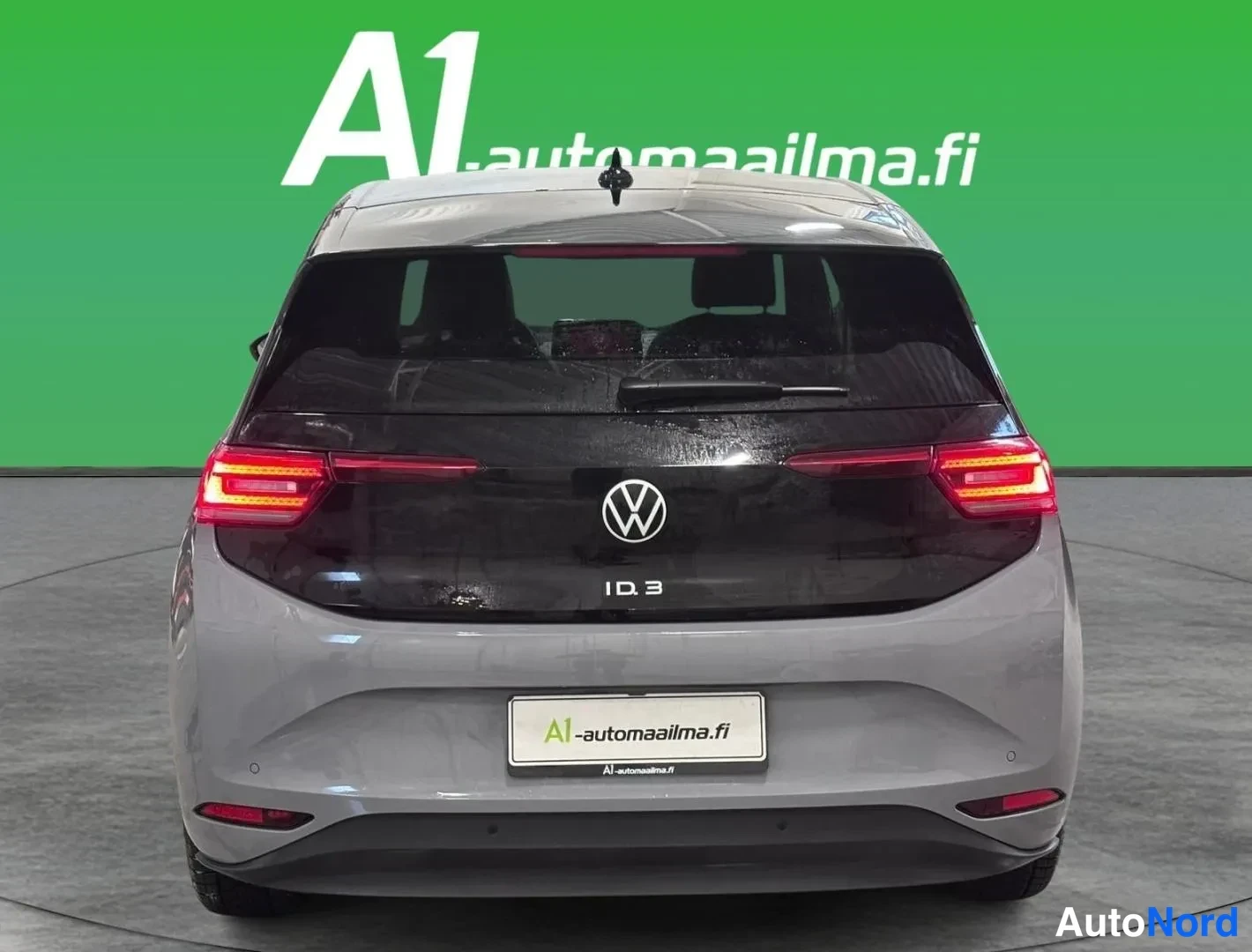 Takaa: Volkswagen ID.3 takaapäin kuvattuna, harmaa korirunko ja musta lasikansi, VW-merkki ja ID.3-tunnus takaluukussa.