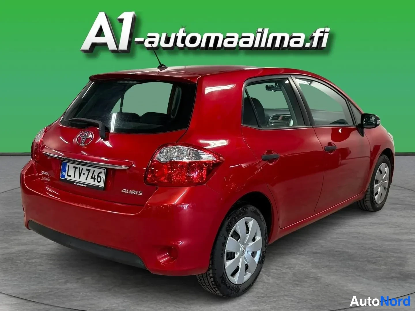 Takaviisto: Punainen Toyota Auris viistosti takaa vasemmalta, takaluukissa Auris-merkintä, rekisteri