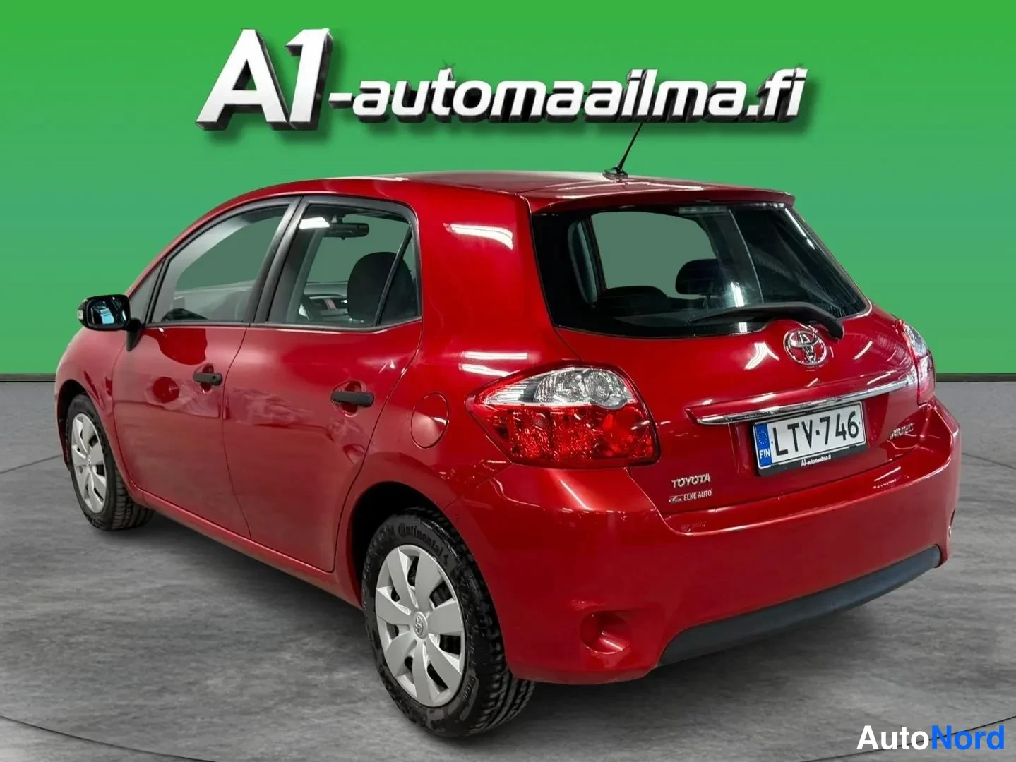 Takaviisto: Punainen Toyota Auris -henkilöauto takanurkkakuvassa vasemmalta; rekisterikilpi, tummat ikkunat ja hopeavanteiset pyörät näkyvät.