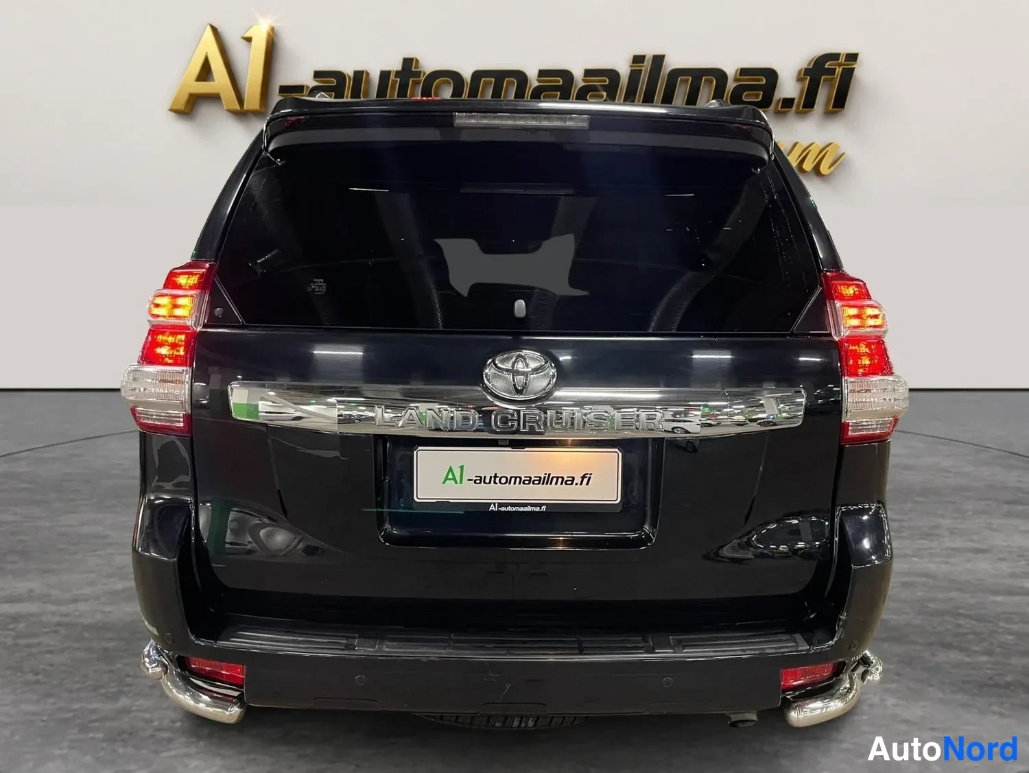 Takaa: Mustan Toyota Land Cruisern takaosa suoraan takaa kuvattuna; näkyvät takavalot, avattava takaluukku ja krominen korokkeisto.