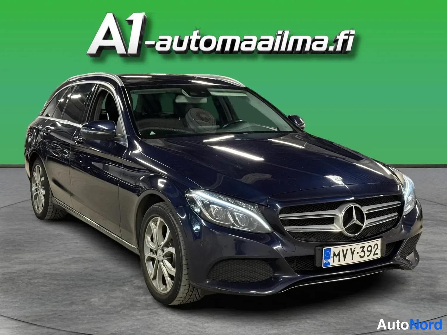 Etuviisto, nokka oikealle: Tummansininen Mercedes-Benz farmariauto kuvattu kolme neljännestä edestä, keulakoodi oikealla; rekisterikilpi.