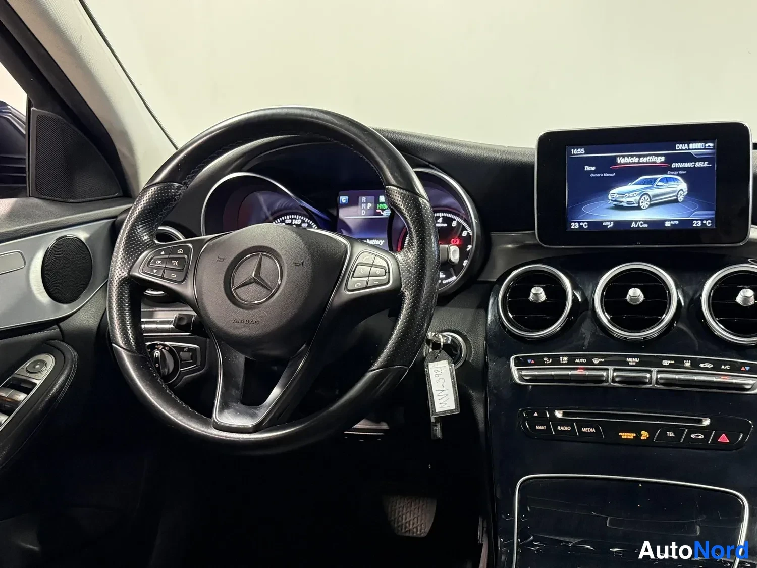 Muu: Kuljettajan puolen sisäkuva: Mercedes-Benzin merkki ohjauspyörässä, mittaristo, käynnistysavaimen nippu ja infotainment-näyttö.