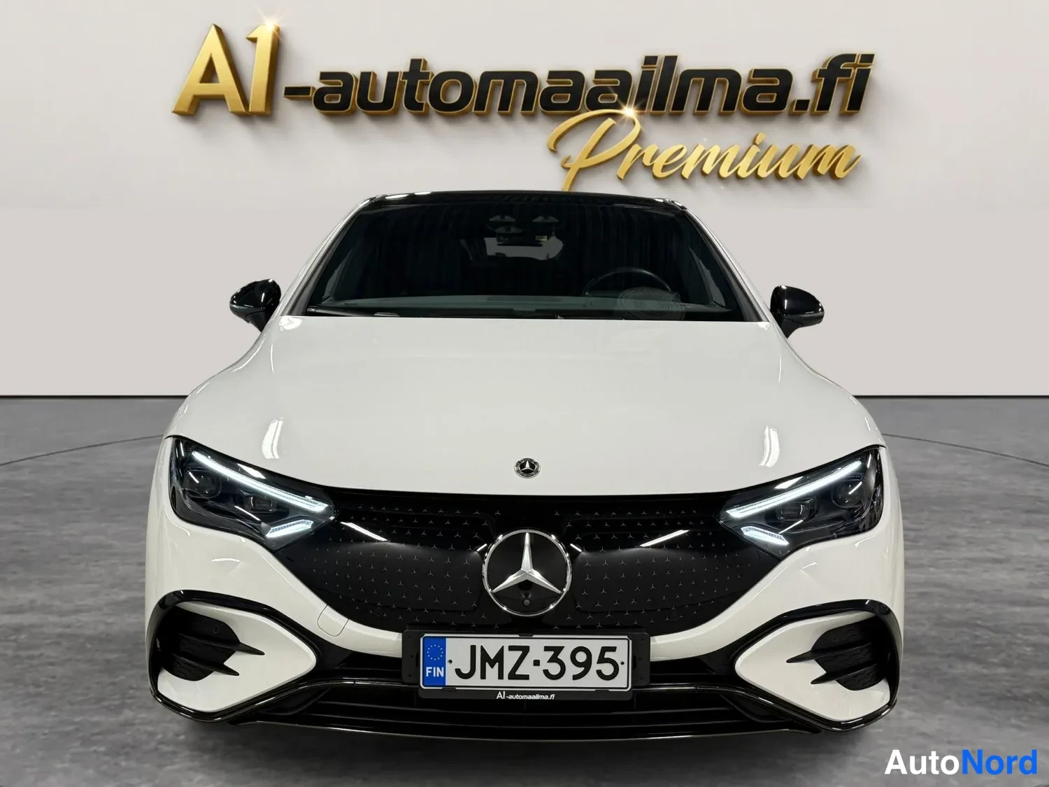 Edestä: Mercedes-Benz EQE:n etunäkymä suoraan edestä: musta tähtikuvioinen säleikkö, tähtiemblemä, LED-ajovalot ja rekisteri.