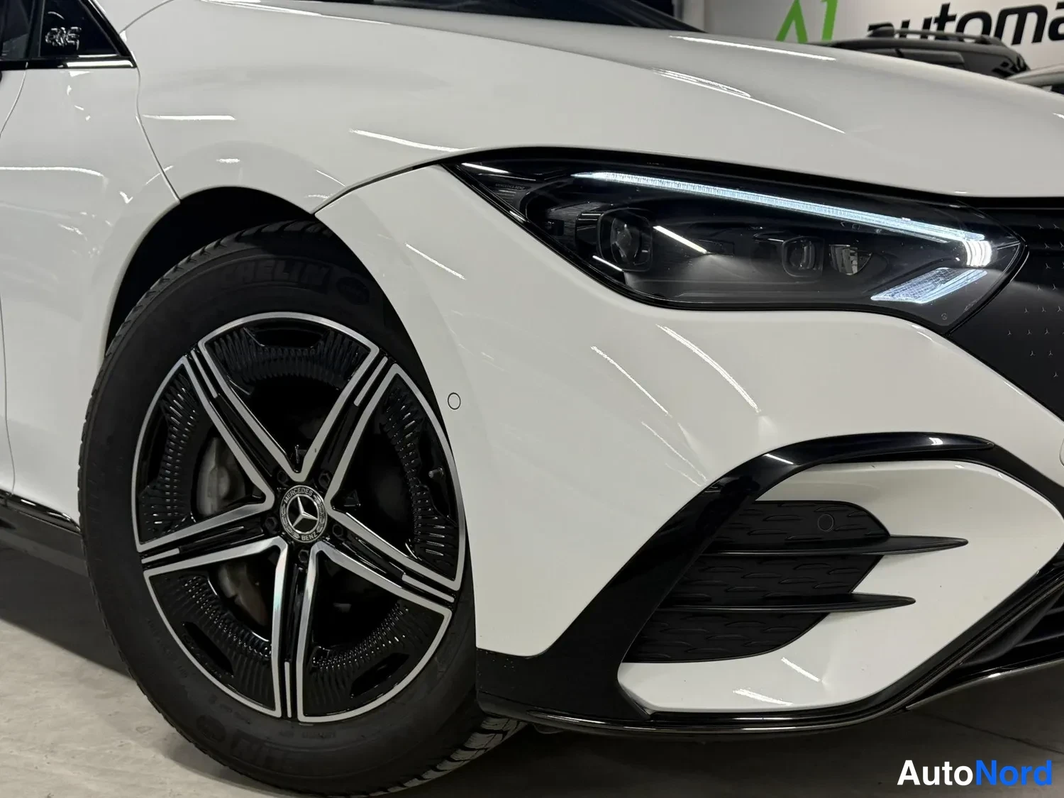 Edestä: Valkoisen Mercedes-Benzin etuosa lähikuvassa: LED-ajovalo ja musta etupuskuri, edessä vasemmanpuoleinen kevytmetallivanne näkyvissä.
