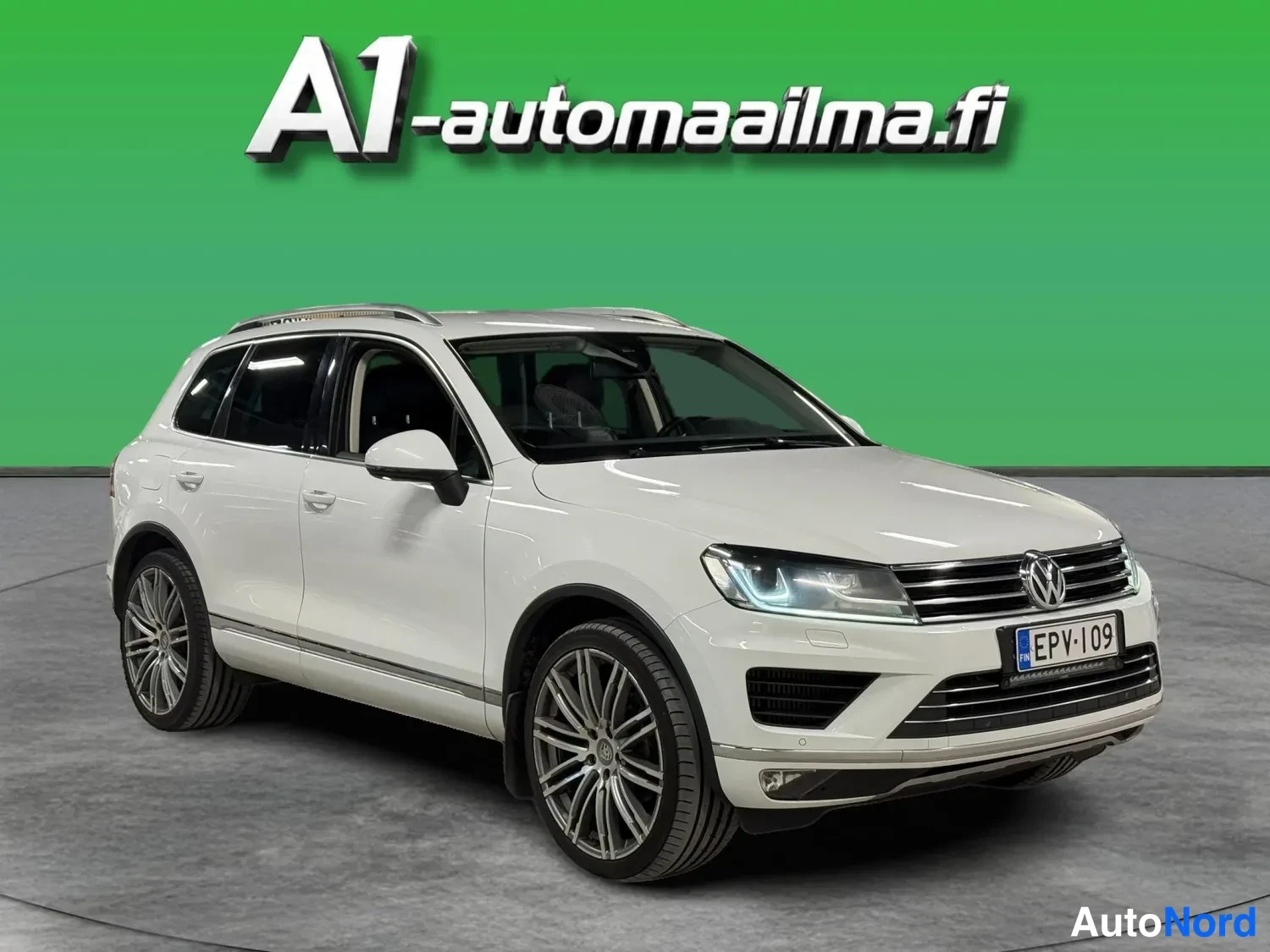 Etuviisto, nokka oikealle: Valkoinen Volkswagen Touareg etukulmasta oikealta, rekisteritunnus.