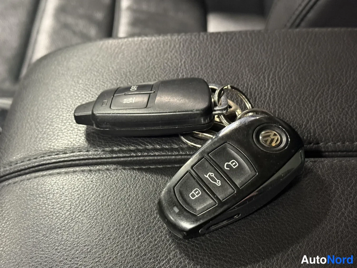 Muu: Kaksi Volkswagen-etäavainta mustaa nahkaistuinta vasten.