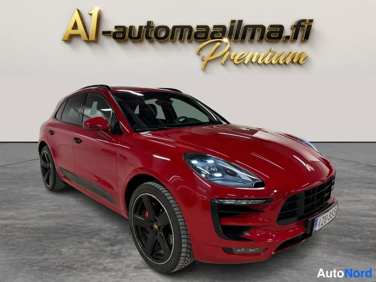 Etuviisto, nokka oikealle: Punainen Porsche Macan edusta kolmannesvasemmalla kuvakulmasta, mustat vanteet ja kattokaiteet näkyvissä.