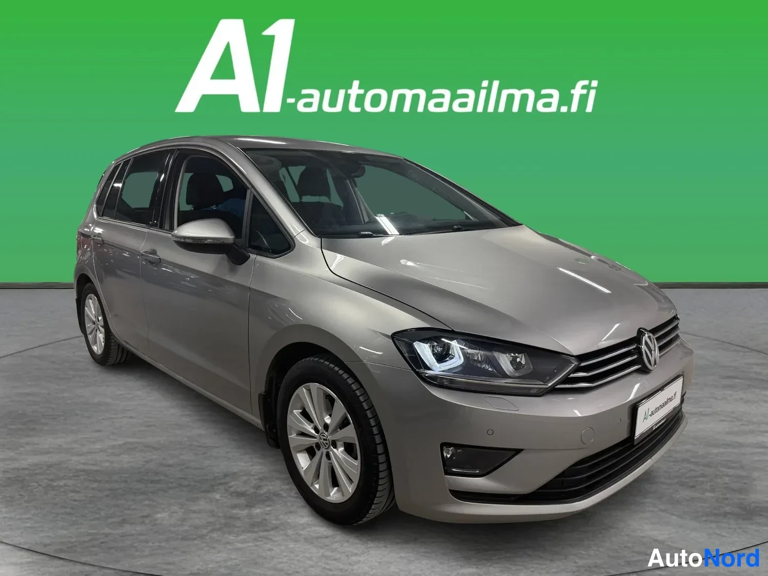 Etuviisto, nokka oikealle: Volkswagen Golf Sportsvanin etukanerva oikealta: harmaa-metallinen kori,Chrome-ritiläinen etusäleikkö, sumuvalot ja A1-automaailman rekisterikilpi.