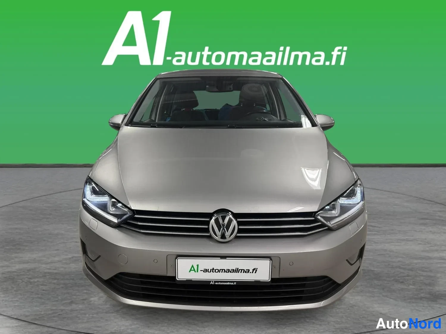 Edestä: Volkswagen Golf Sportsvanin suora etunäkymä: harmaa-metallinen kori, Chrome-reunustettu etusäleikkö VW-emblemillä, LED-tyyppiset ajovalot.