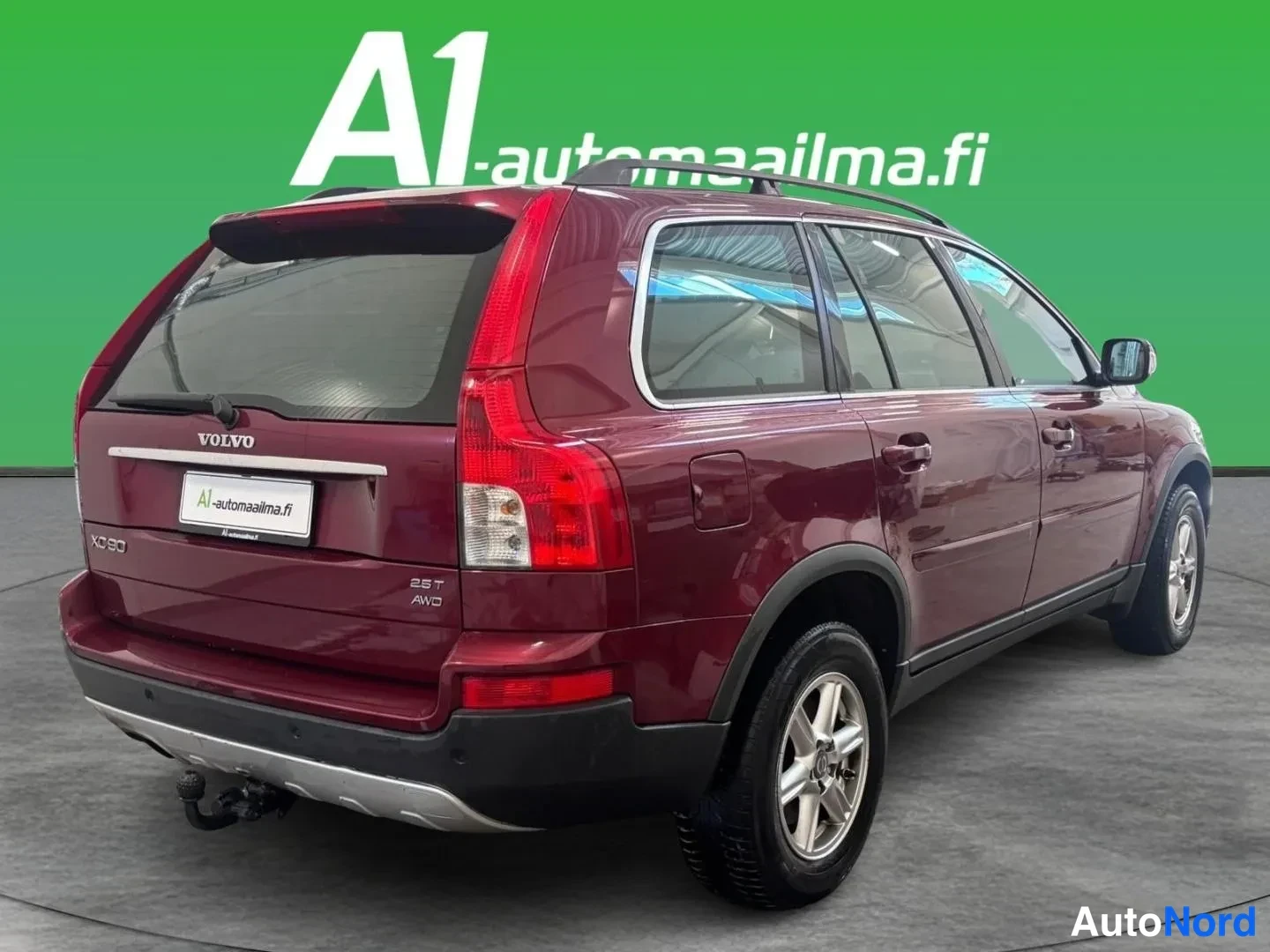 Takaviisto: Takaviistosta kuvattu tummanpunainen Volvo XC90, takaluukki, VOLVO-merkintä, XC90- ja 2.5T AWD-embleemit, kattokaiteet ja vetokoukku näkyvissä.