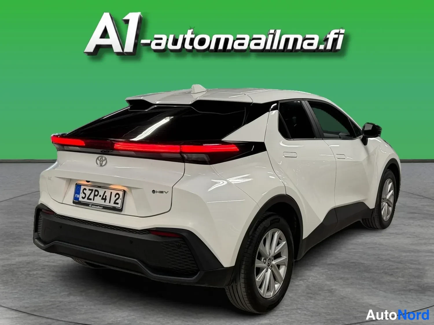 Takaviisto: Toyotan takakolmasosa: valkoinen kori, kattospoileri, korkea musta takaluukku ja punainen takavaloyksikkö, rekisteritunnus.