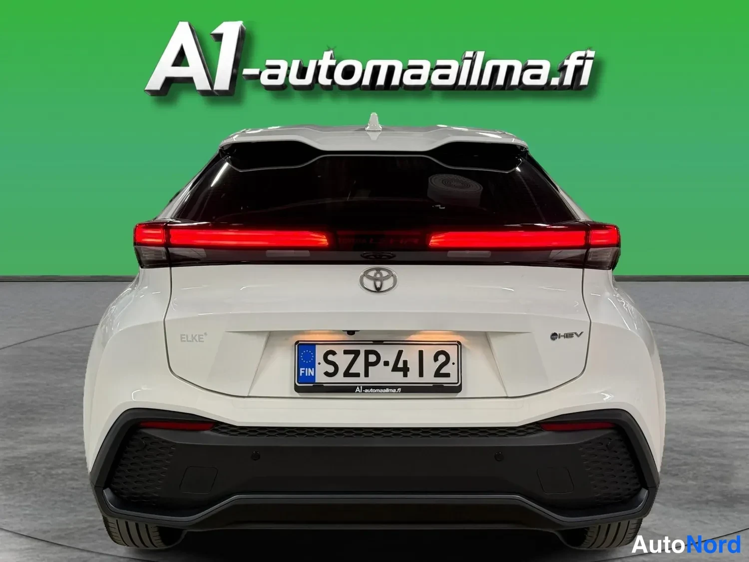 Takaa: Valkoisen Toyota C-HR:n takapää suoraan takaa; punaiset takavalot, Toyota-merkki, HYBRID-merkintä ja rekisterikilpi näkyvät.