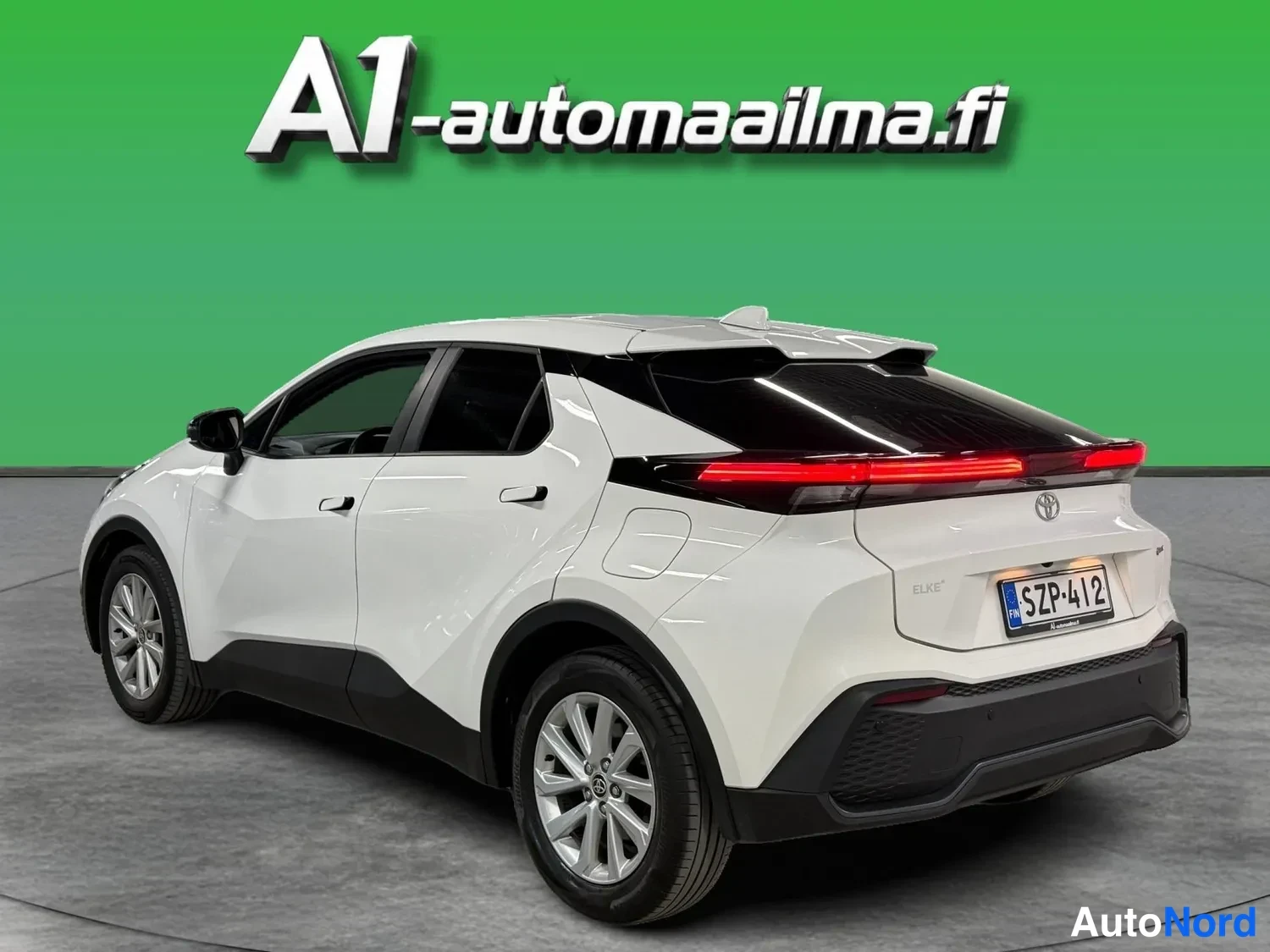 Takaviisto: Valkoinen Toyota C-HR takaviistosta kuvattuna; näkyvät left flank, takapää, kattosiipi ja hopeavanteiset pyörät.