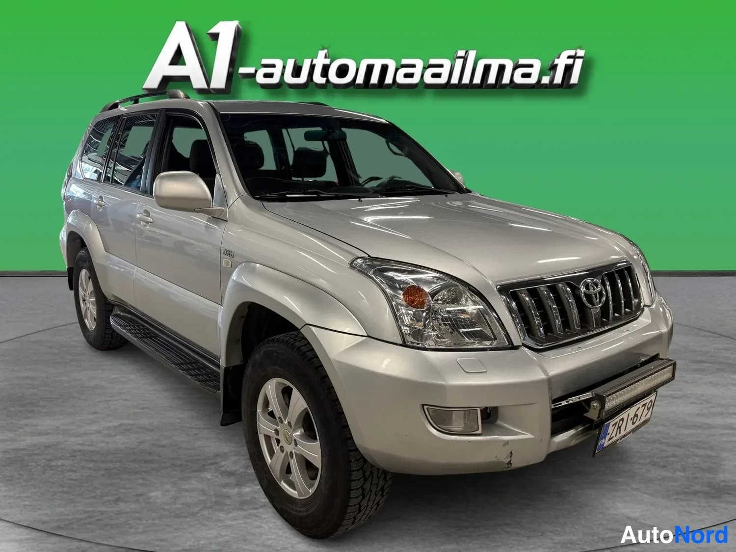 Etuviisto, nokka oikealle: Hopeanvärinen Toyota Land Cruiser -maastauto kuvattu kolmivartalokulmasta etuosasta oikealle, konepelti, etusäleikkö ja ajovalot näkyvät.