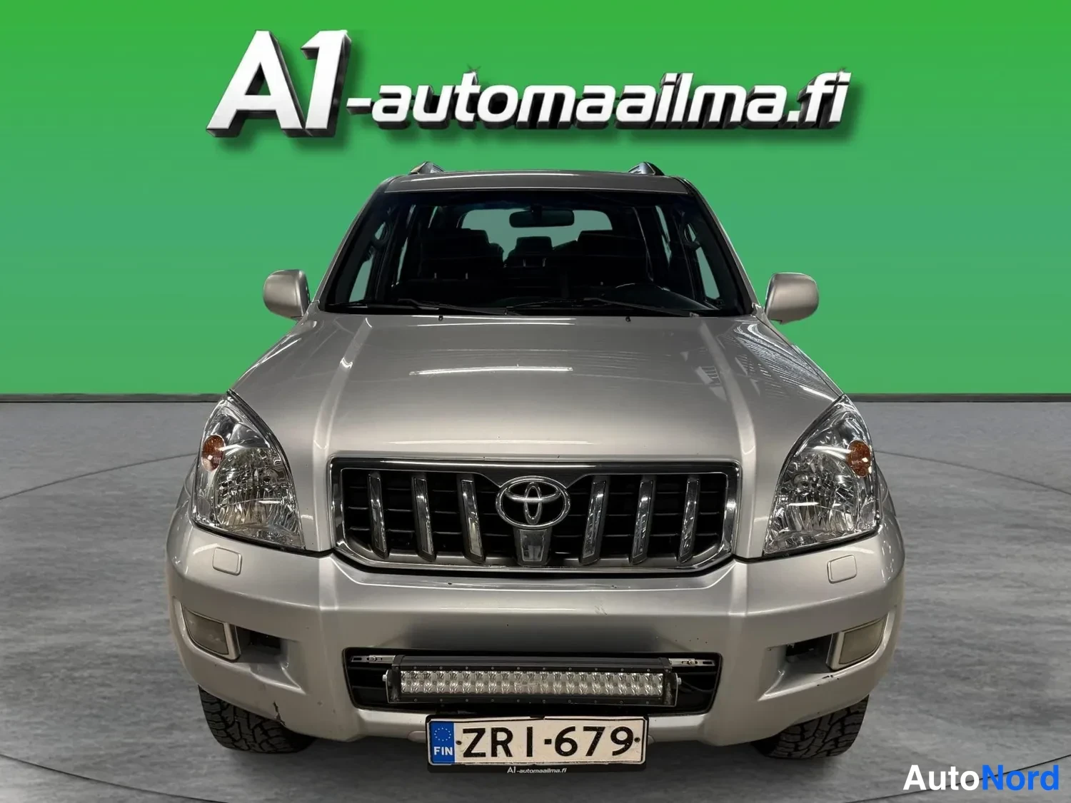 Edestä: Etukuvassa hopeanvärinen Toyota Land Cruiser, etusäleikkö ja ajovalot suoraan edestä.