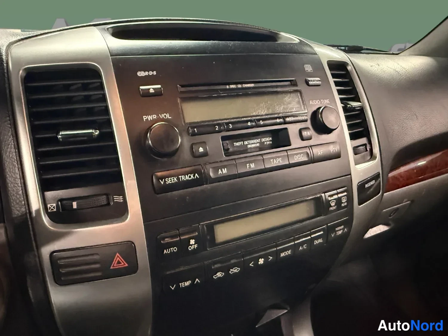 Muu: Kojelaudan keskiosan lähikuva: radiota ja manuaalista ilmastointipaneelia, jossa lukee AUTO, OFF, A/C, DUAL, TEMP, MODE.