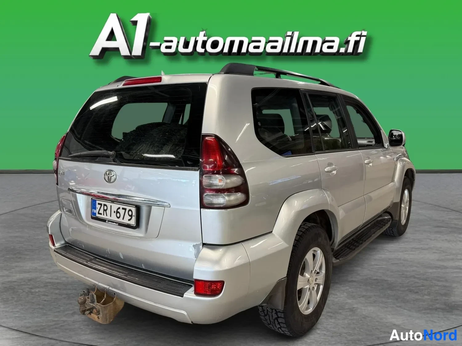Takaviisto: Auton takaosa ja oikea sivu kolmen neljäsosan kulmasta: hopea Toyota, kattoteline, sivuhalkaisijat ja rekisteritunnus.