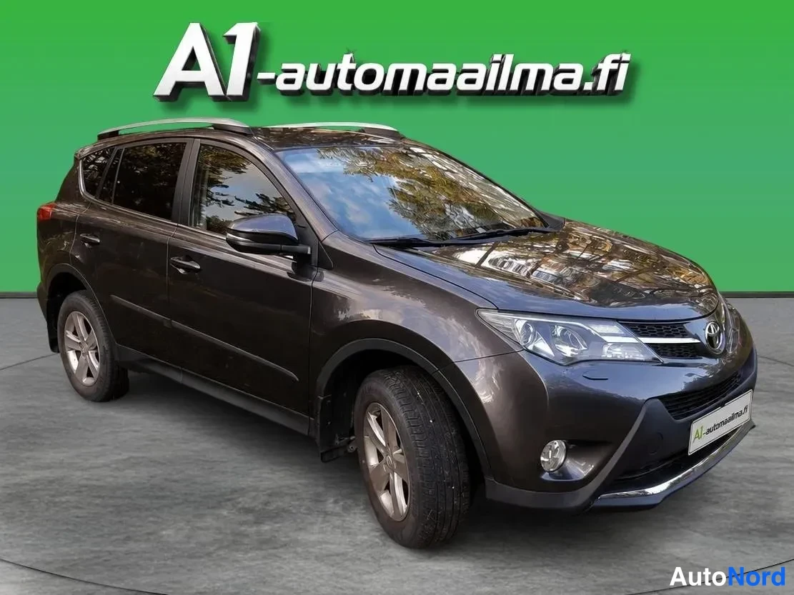 Etuviisto, nokka oikealle: Tummanruskea Toyota RAV4 etuviistöstä oikealta, kattokaiteet ja hopeavanteet näkyvissä.