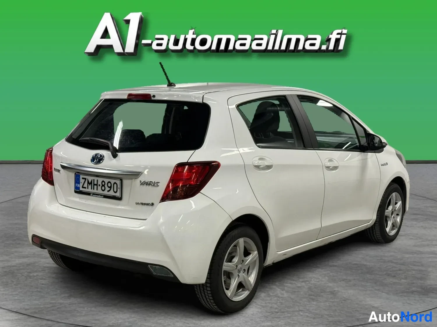 Takaviisto: Valkoisen Toyota Yarisin takakulma: avattava takaluukki, takavalot, rekisterikilpi ja vasen kylki.