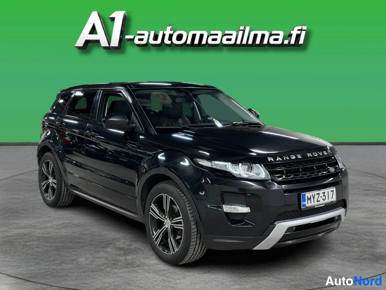 Etuviisto, nokka oikealle: Musta katumaasturi etuosasta oikeasta nurkasta kuvattuna, etusäleikkö ja etuvalot näkyvissä, konepellillä RANGE ROVER -teksti ja rekisteritunnus.