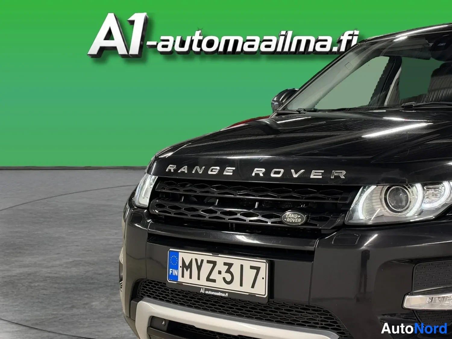 Edestä: Mustan Range Rover Evoguen keula lähikuvassa, rekisteritunnus, LAND ROVER-merkki etusäleikössä.