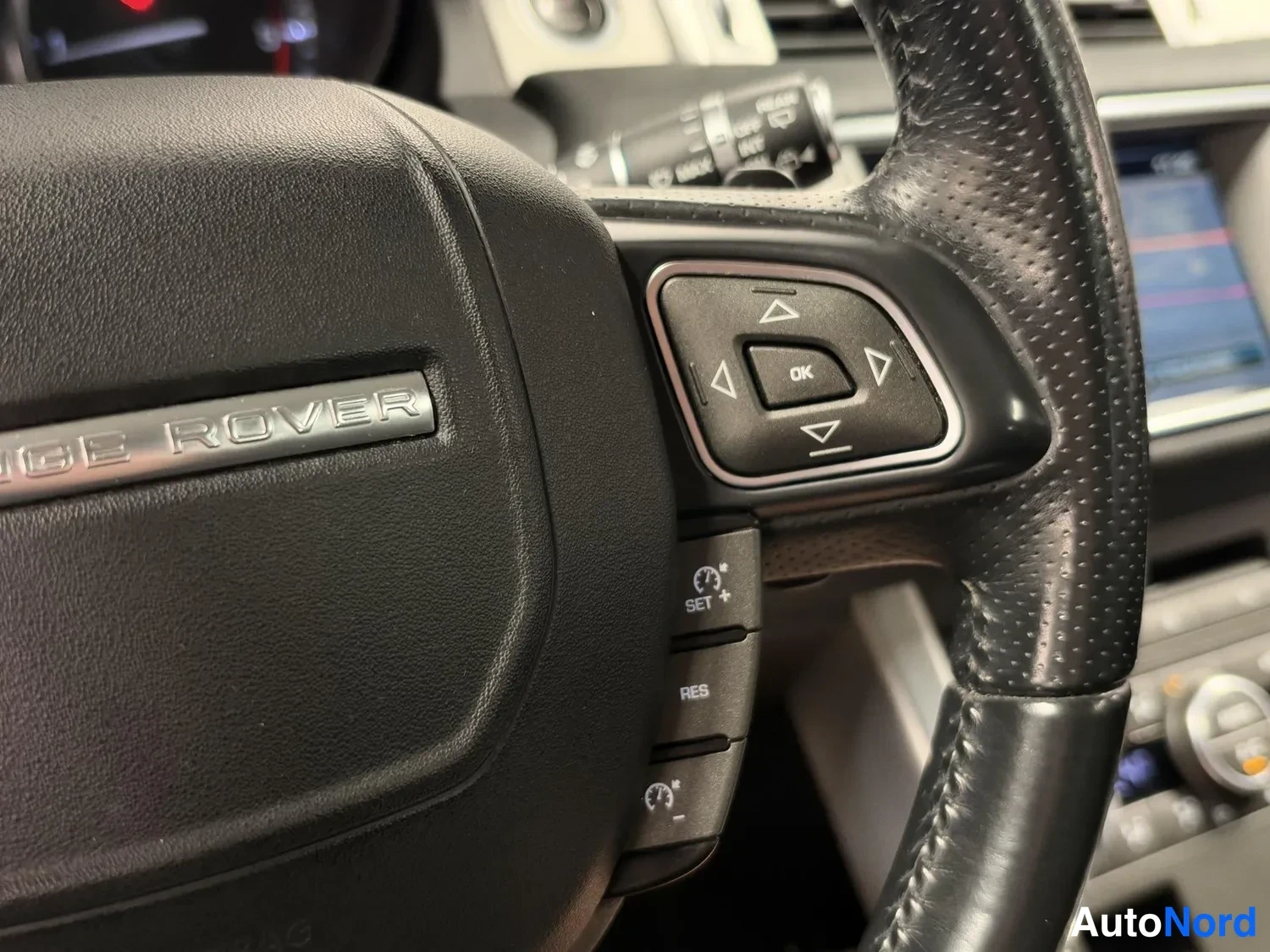 Yksityiskohta: RANGE ROVER -merkitty ohjauspyörä ja sen oikeanpuoleiset näppäimet sekä cruise control -kytkimet
