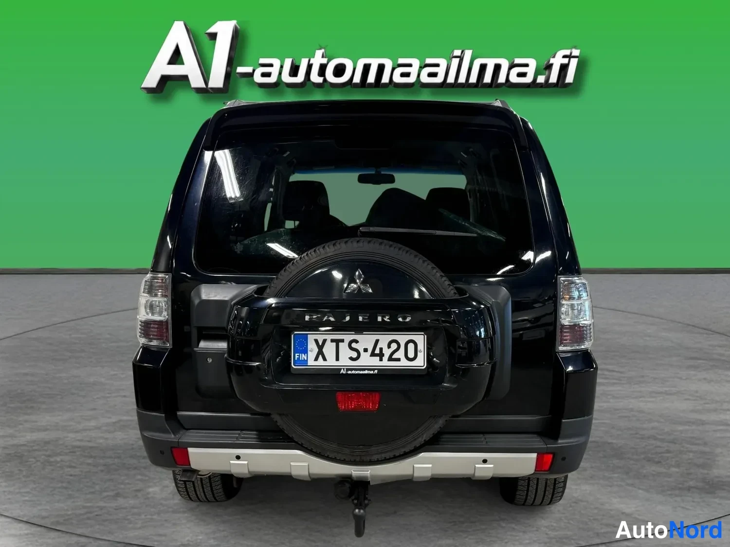 Takaa: Musta Mitsubishi Pajeron perä näkyvissä: vararenkaalla kiinnitetty kuvio, rekisteritunnus, Pajero-teksti ja vetokoukku.