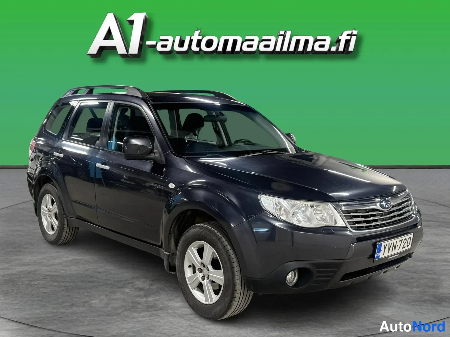 Etuviisto, nokka oikealle: Mustansininen Subaru Forester -maastokuorma-auto kolmivartalokuva edestä oikealta, rekisteritunnus