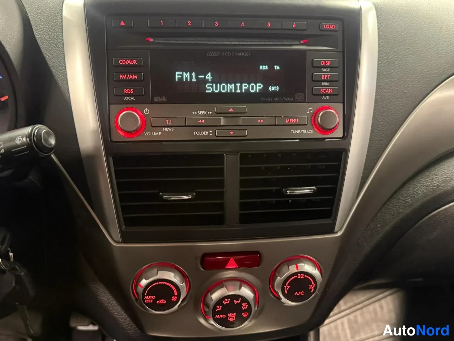 Muu: Radio-/multimedia- ja ilmastointipaneelin lähikuva: näytössä 'FM1-4 SUOMIPOP', yläreunassa CD-aukko ja LOAD-painike, alareunassa A/C- ja AUTO-OFF-merkityt ilmas