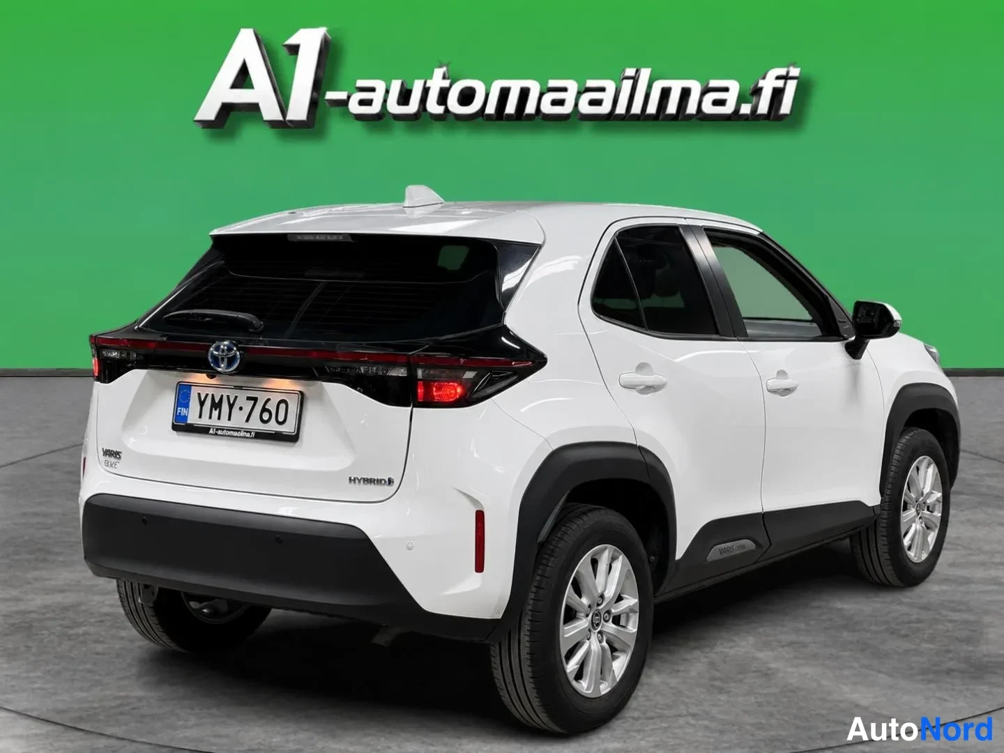 Takaviisto: Valkoisen Toyota Yaris Crossin takakulmanäyttö; rekisteri, HYBRID-merkintä takaluukussa ja vihreä tausta.