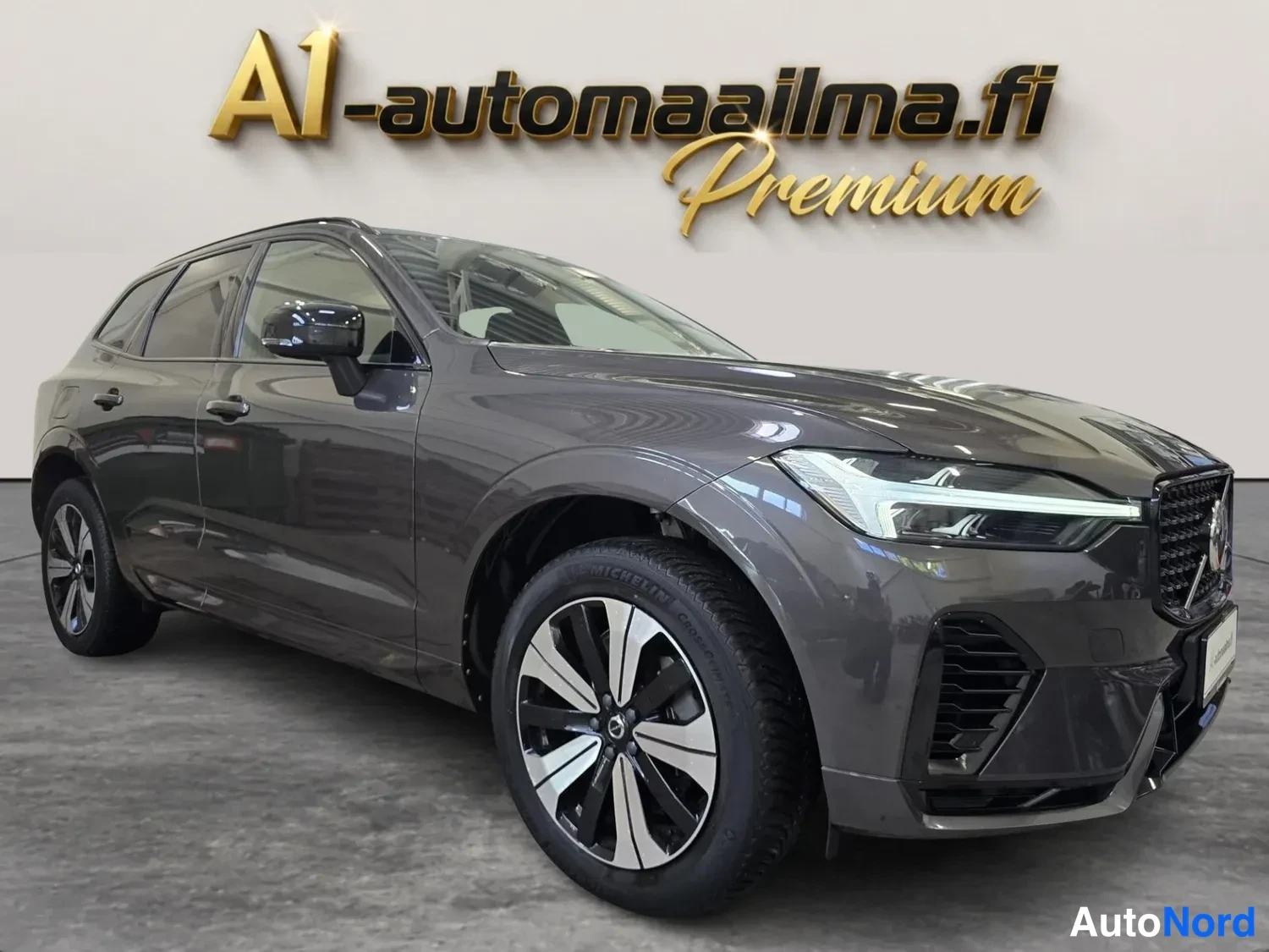 Etuviisto, nokka oikealle: Tummanharmaa farmarimallinen auto kuvattu etukulmasta, keula oikealla, tallissa.
