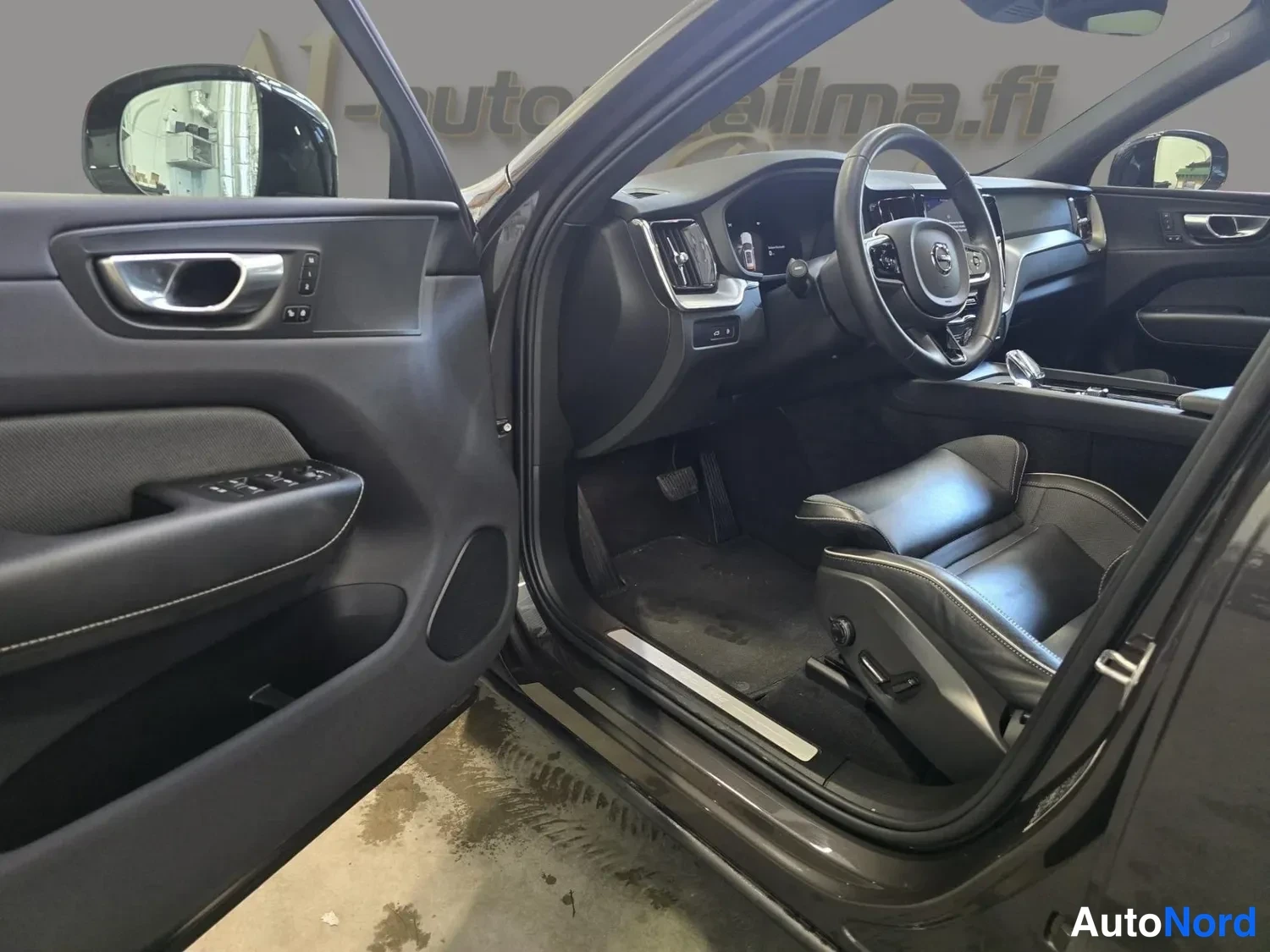Muu: Volvo XC60:n etuistuin ja etuoven aukaisu: mustaa nahkaa istuin, oviverhoilu ja mittaristö näkyvät auton sisältä.