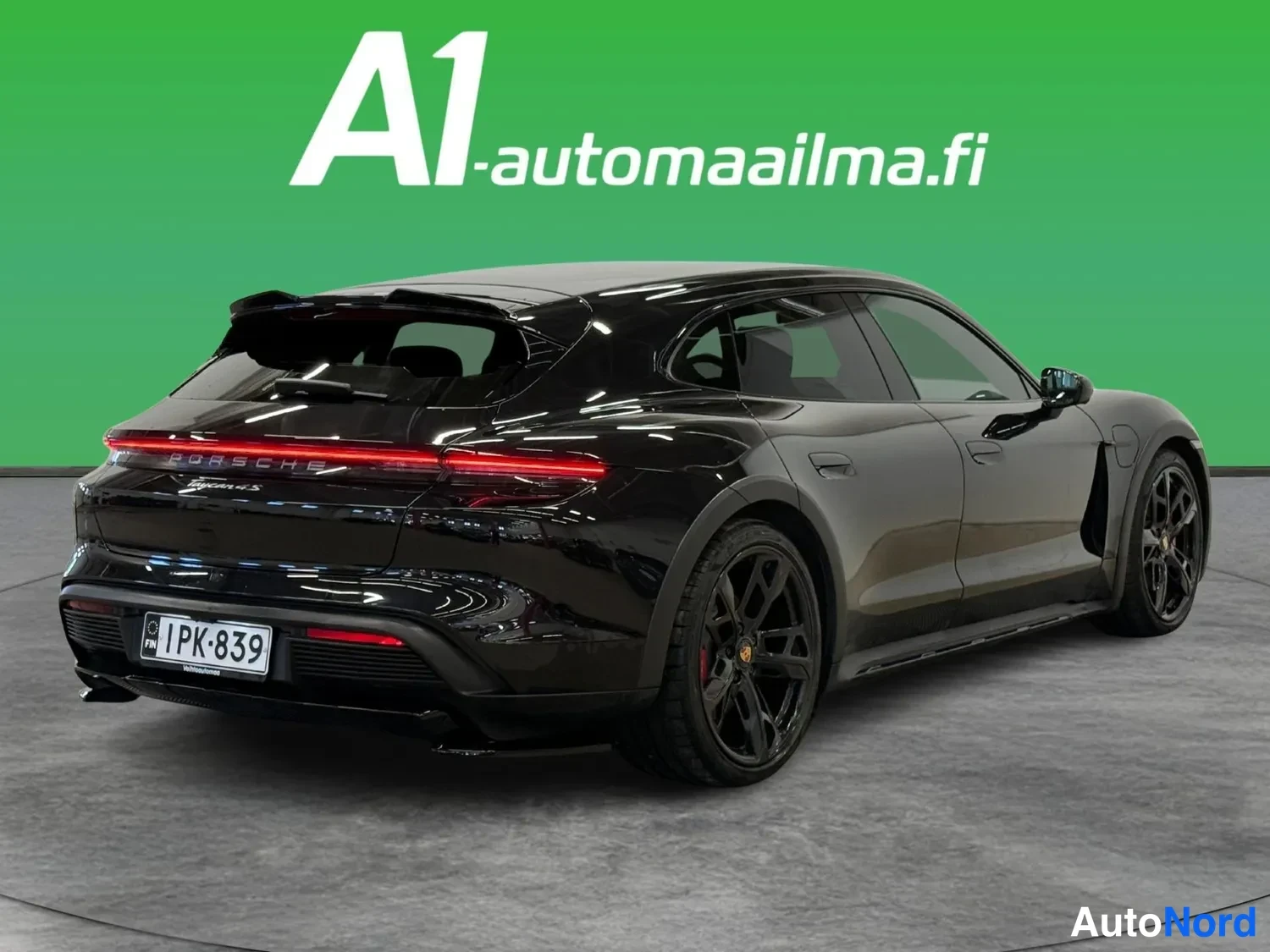 Takaviisto: Musta Porsche Taycan Cross Turismo taka kolmasosa oikealta; tummat vanteet, punaiset jarrusatulat, rekisterikilpi.