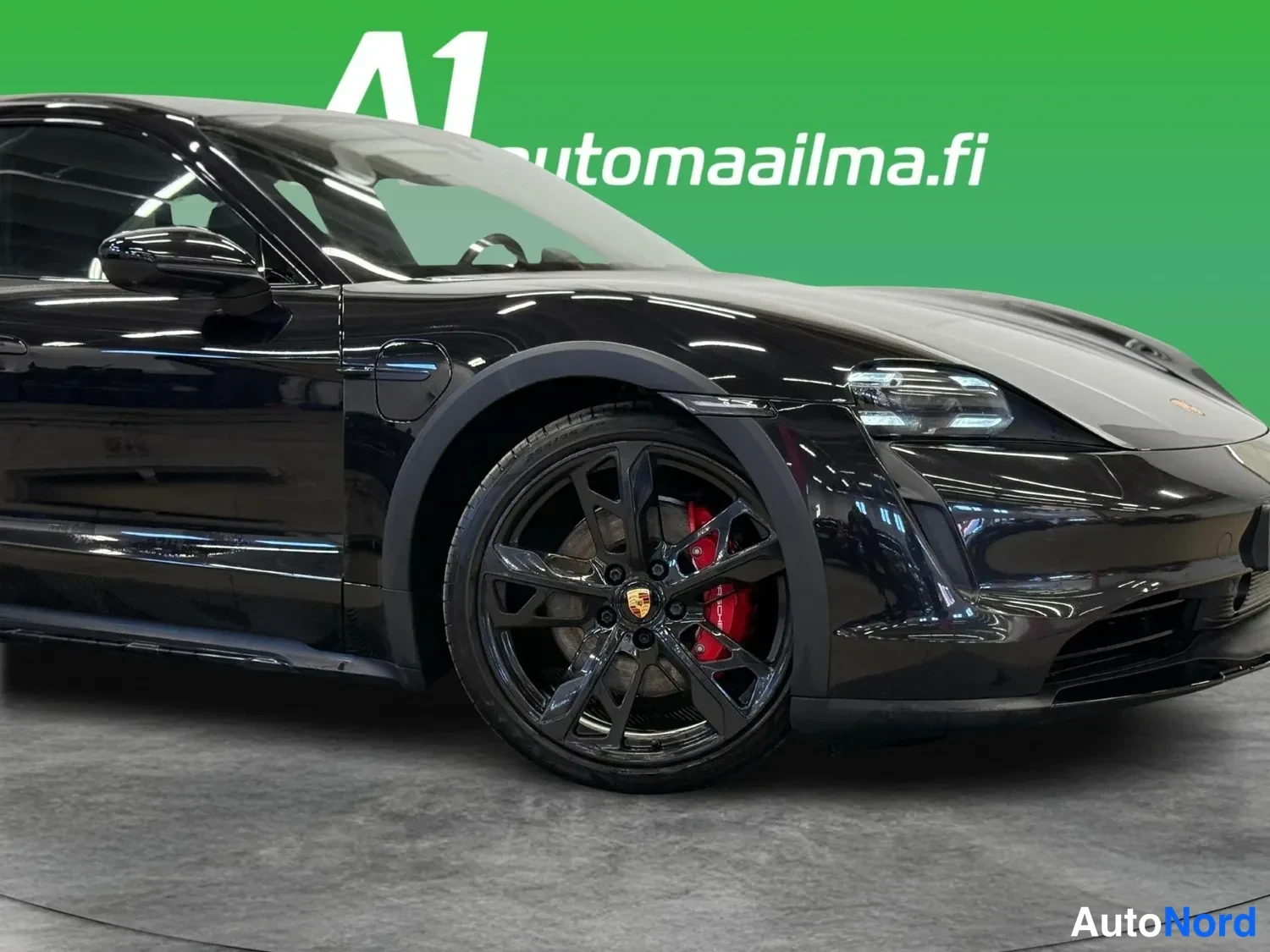Etuviisto, nokka oikealle: Mustan Porsche Taycanin keula ja etummainen sivupinta lähikuvassa; tumma vante ja punainen jarrusatau näkyvät.