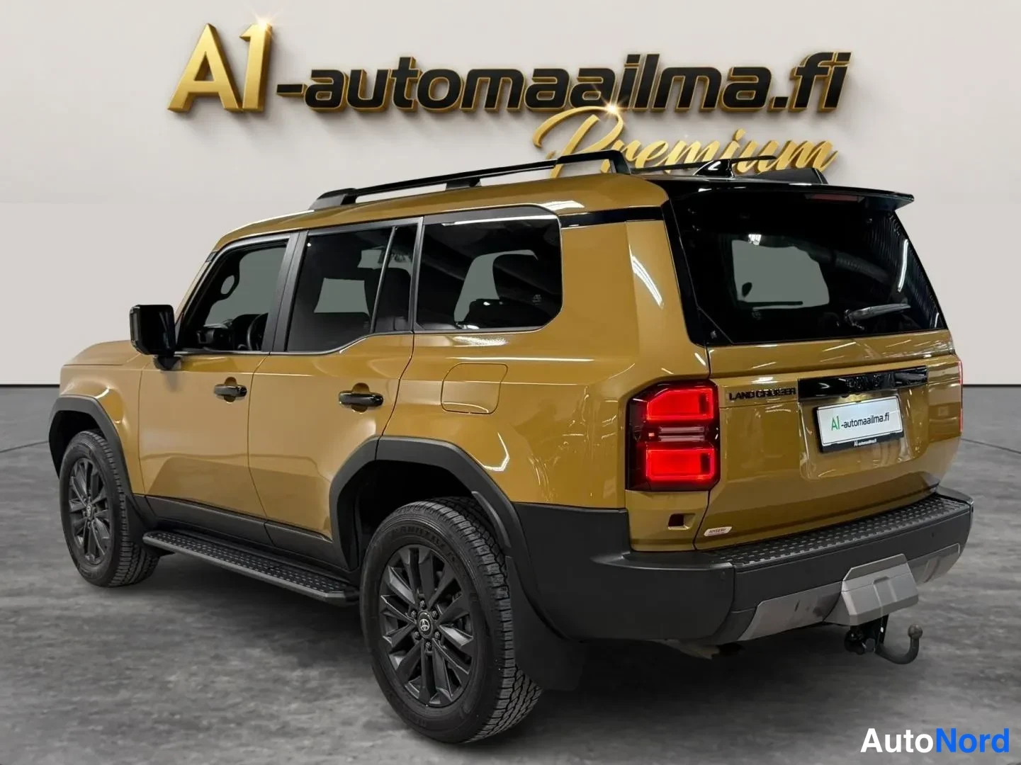 Takaviisto: Toyota Land Cruiser takaviistosta kuvattuna: kullankeltainen runko, musta katto, tummat vanteet, sivukaiteet, punaiset takavalot ja vetokoukku.