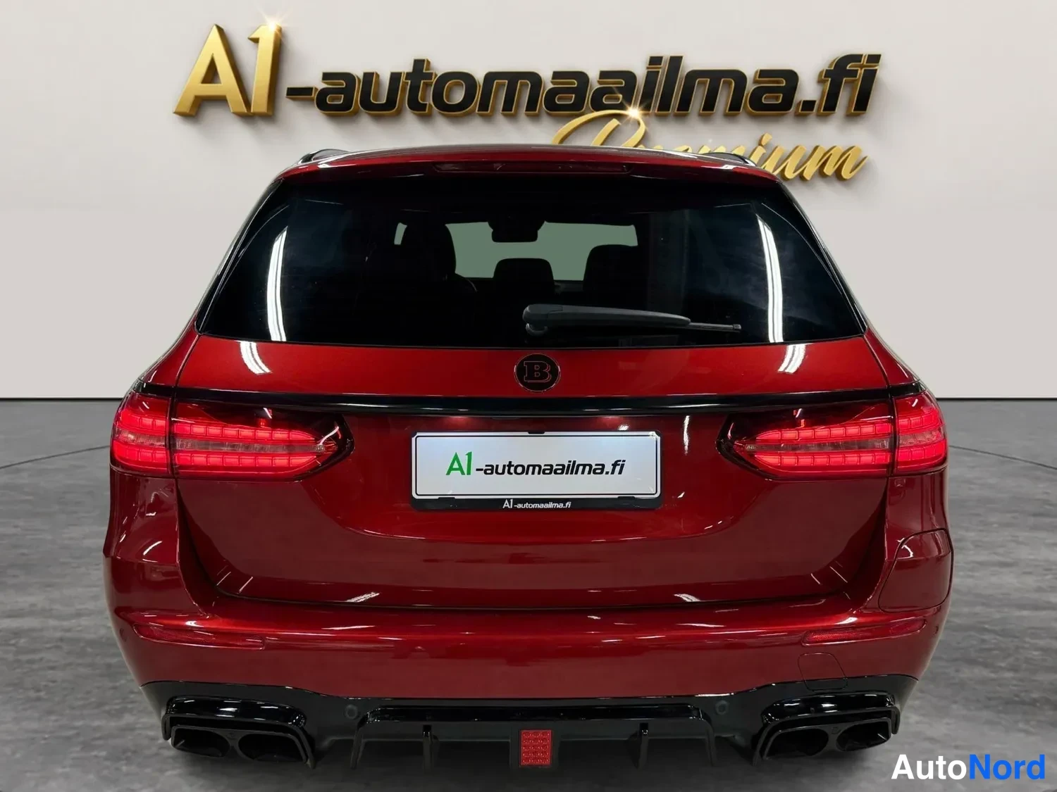 Takaa: Punaisen Mercedes-Benz farmariauton takaosa suoraan takaa kuvattuna, tummat takavalot ja musta takapuskurin lisä.