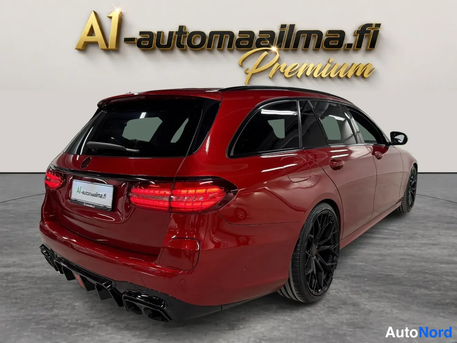 Takaviisto: Punainen Mercedes-Benz farmariauto takaa vasemmalta kulmasta kuvattuna, mustat takavalojen kehykset ja mustat kevytmetallivanteet.