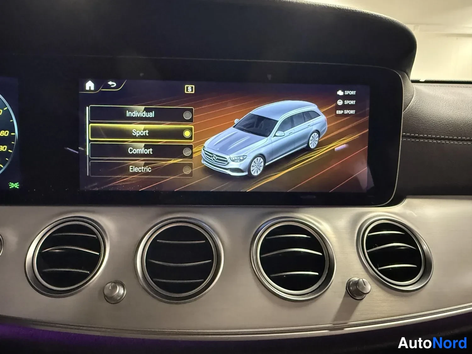 Muu: Infotainment-näyttö näyttää ajotilavalikon vaihtoehdoilla Individual, Sport, Comfort ja Electric sekä auton graafisen kuvan; 'Sport' on valittuna.