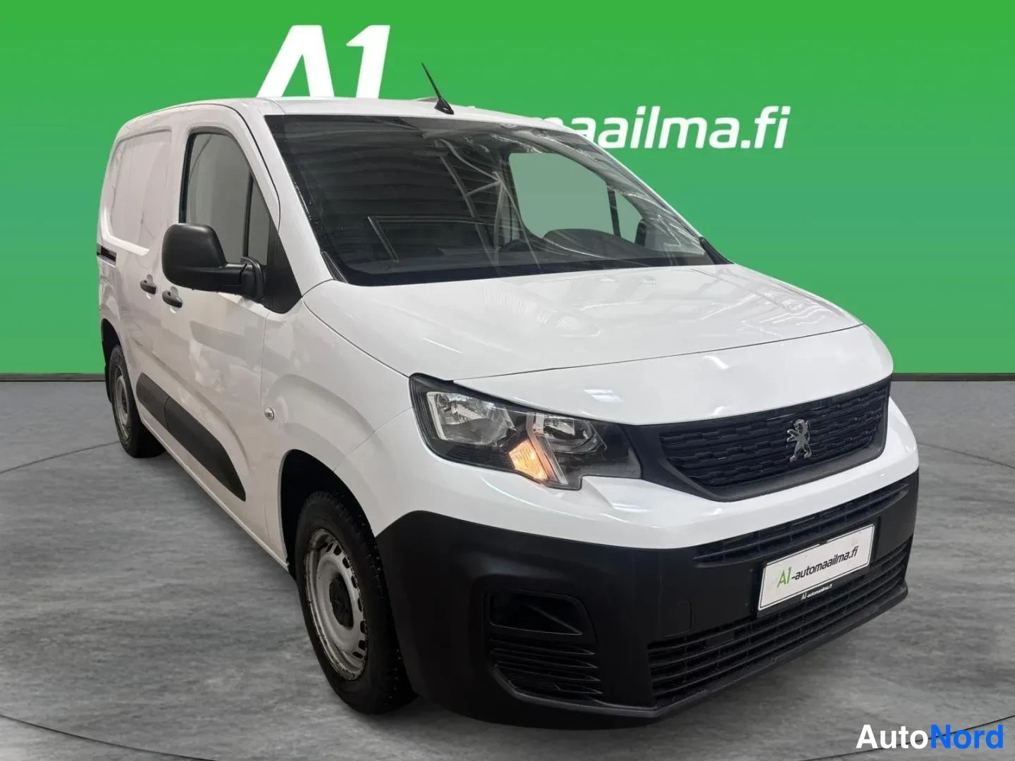 Etuviisto, nokka oikealle: Peugeot Partner -pakettiauto valkoisena etuviistöstä oikealta, musta etusäleikkö ja löysät pyöränkantokilvet näkyvissä.