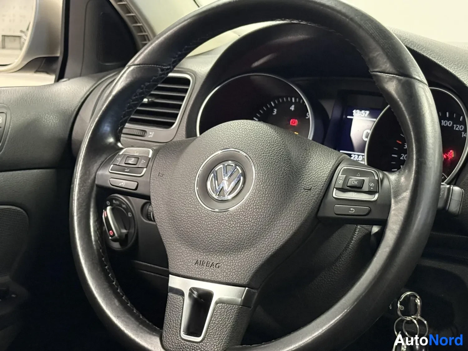 Muu: Ohjauspyörän lähikuva: Volkswagen-logon keskellä, AIRBAG-teksti, monitoimipainikkeet ja osa mittaristosta näkyvät; avain on lukossa.