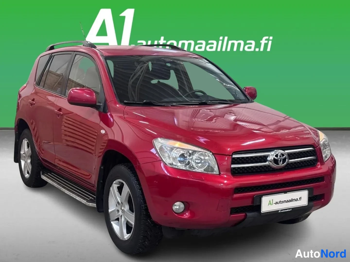Etuviisto, nokka oikealle: Punainen Toyota RAV4 etuviistossa oikealta, kylki ja keula näkyvät kattokaiteineen.