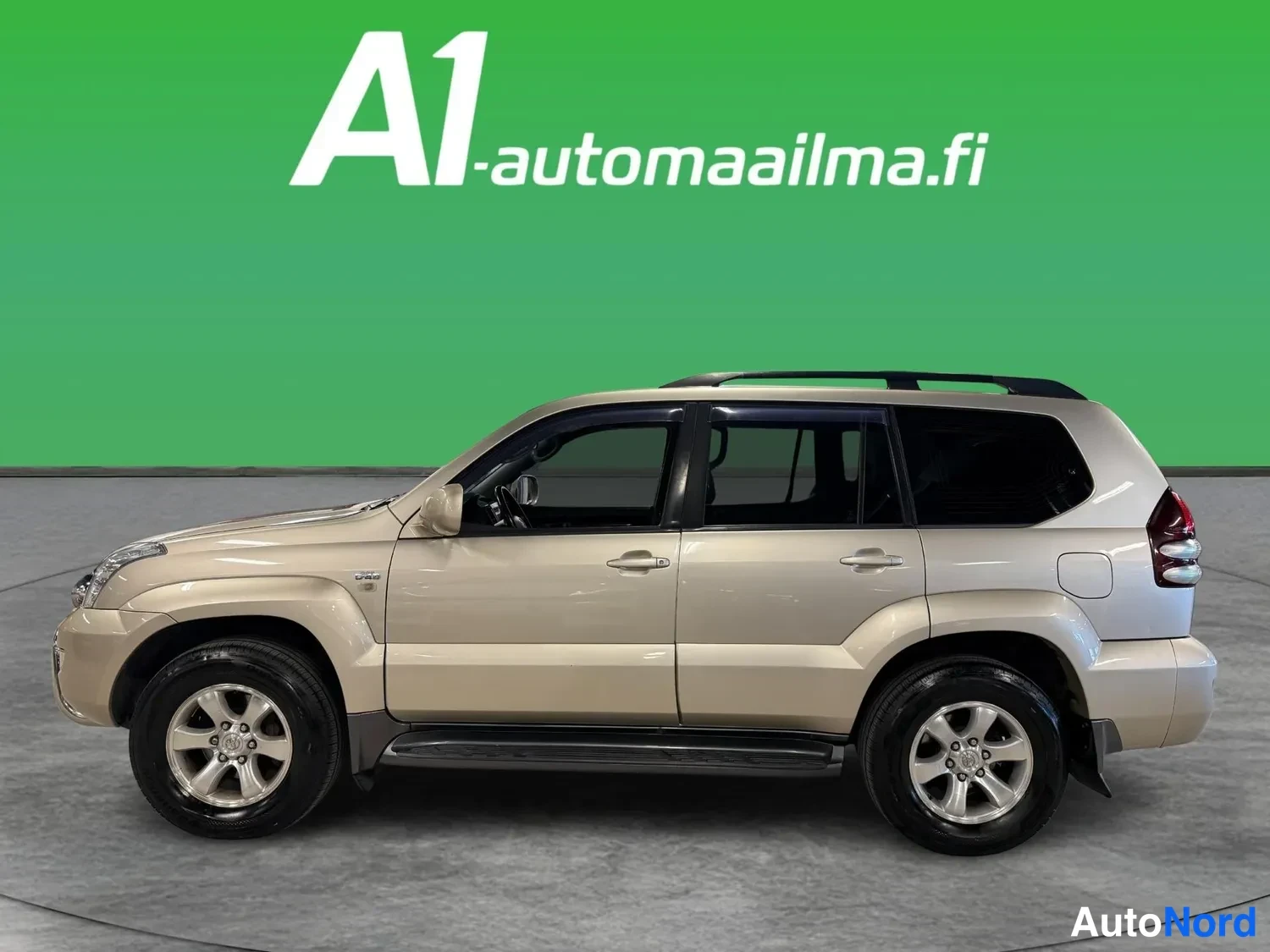 Sivulta: Beige Toyota Land Cruiser -urheilumaastopyörä kokonaan kyljestä vasemmalta, kattotelineet ja sivulaitteet näkyvissä.