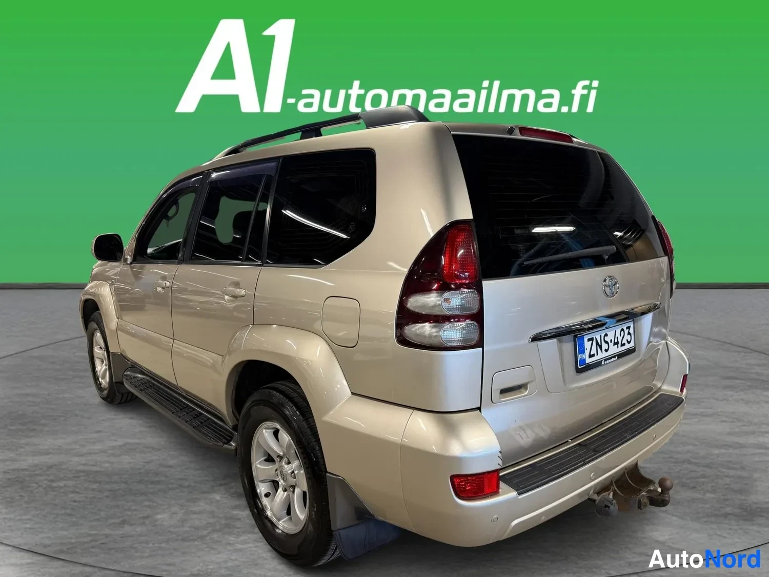 Takaviisto: Beige Toyota Land Cruiser -urheilumaastopyörä takaoviistosta vasemmalta, perä ja vasen kylki näkyvissä, rekisteri.
