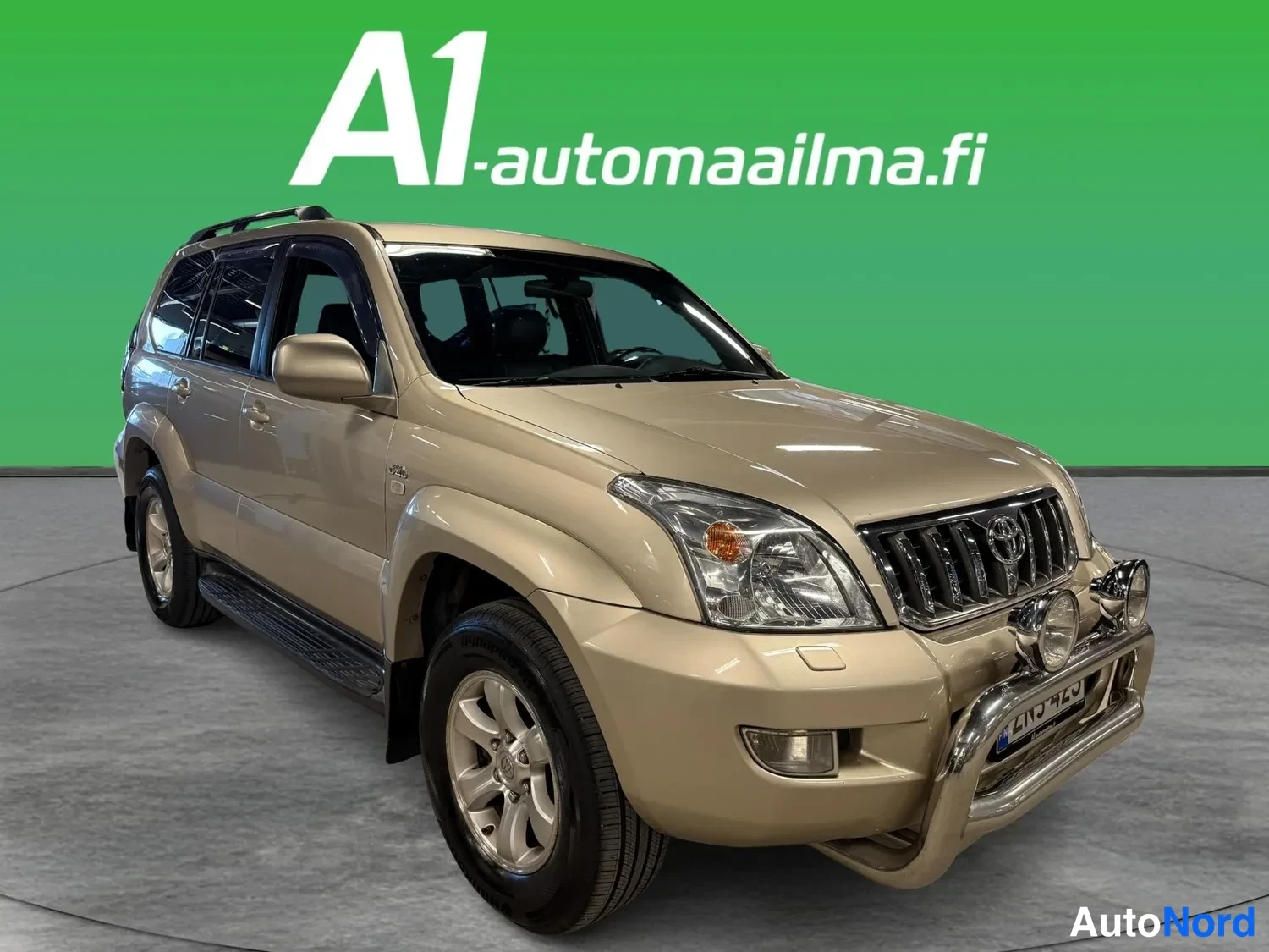 Etuviisto, nokka oikealle: Beige Toyota Land Cruiser -maastauto etukulmasta oikealta, kêytäväpalkki ja ajovalot edessä.