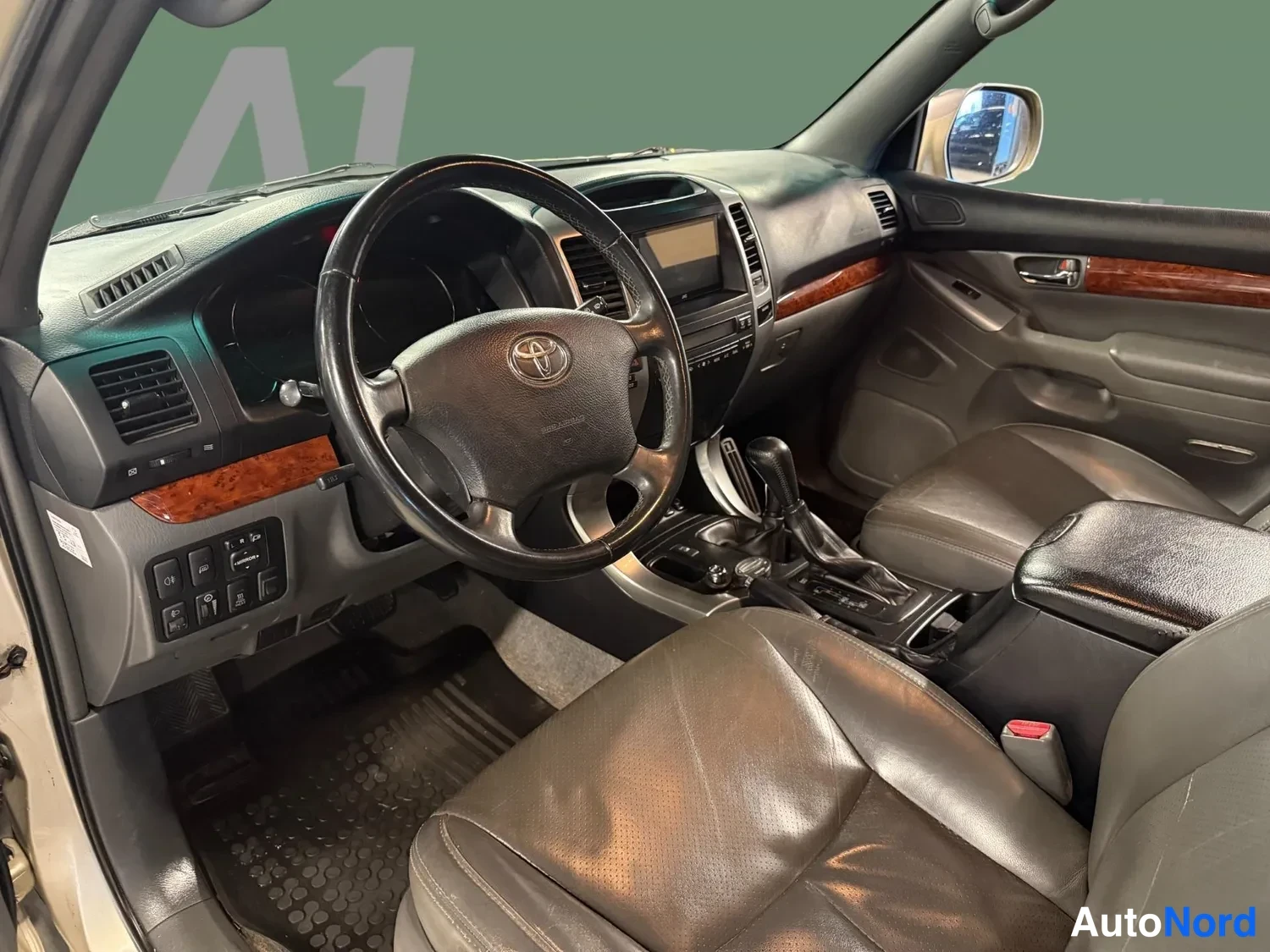 Muu: Sisätilakuva Toyota Land Cruiserista: ohjaamo näkyy kuljettajan puolelta, nahkaverhoillut istuimet, Toyota-merkkinen ohjauspyörä, puynkuorioinen kojelauta, kesk