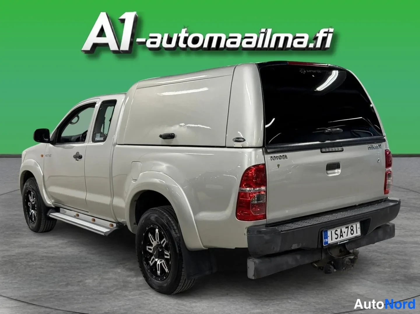Takaviisto: Hopeanvärinen pickup taka–sivukulmasta; peitelistallinen lavakate, punaiset takavalot ja rekisteritunnus.