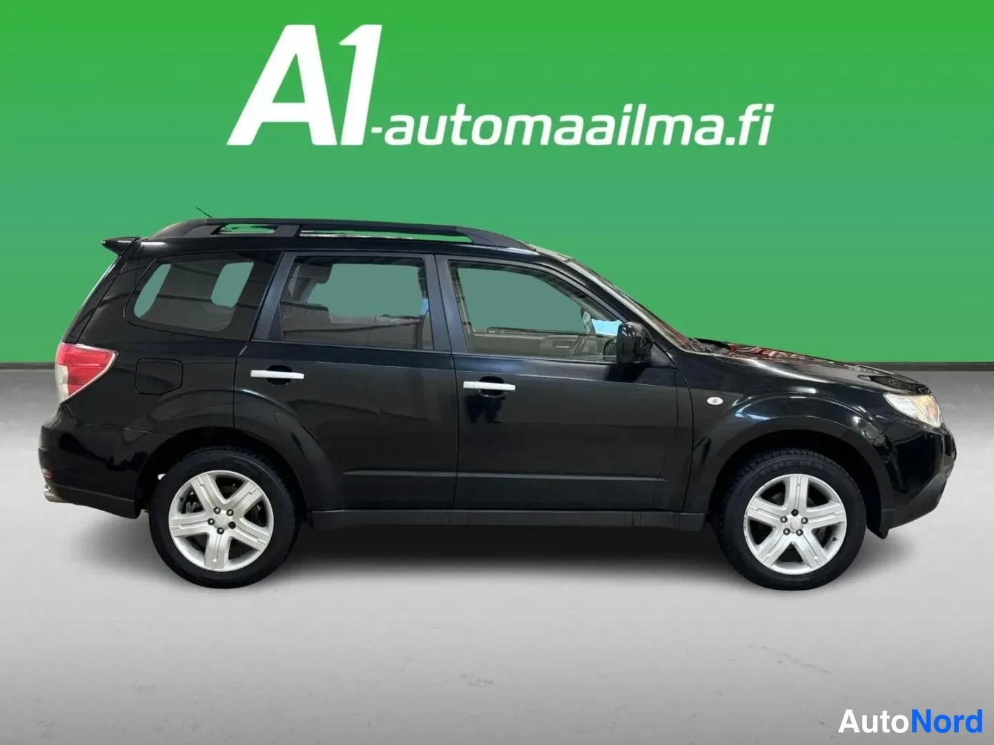 Takaviisto: Subaru Forester -tyylinen SUV sivusta takaa katsottuna, taa takaosan takavalot ja puskuri ovat näkyvissä. Auto on tummansininen ja siinä on kattokaiteet. Tausta