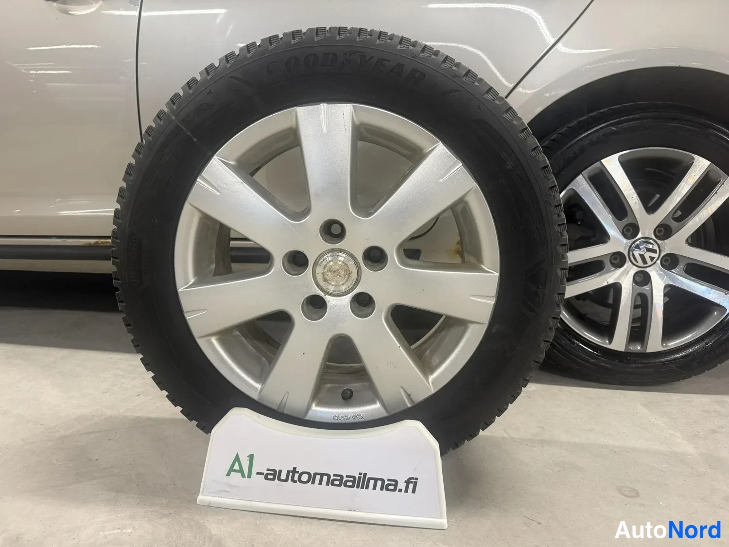 Yksityiskohta: Kassin rengas Goodyear-hilaviilevalla alumiinivanteella, taustalla auton kylki ja toinen rengas.