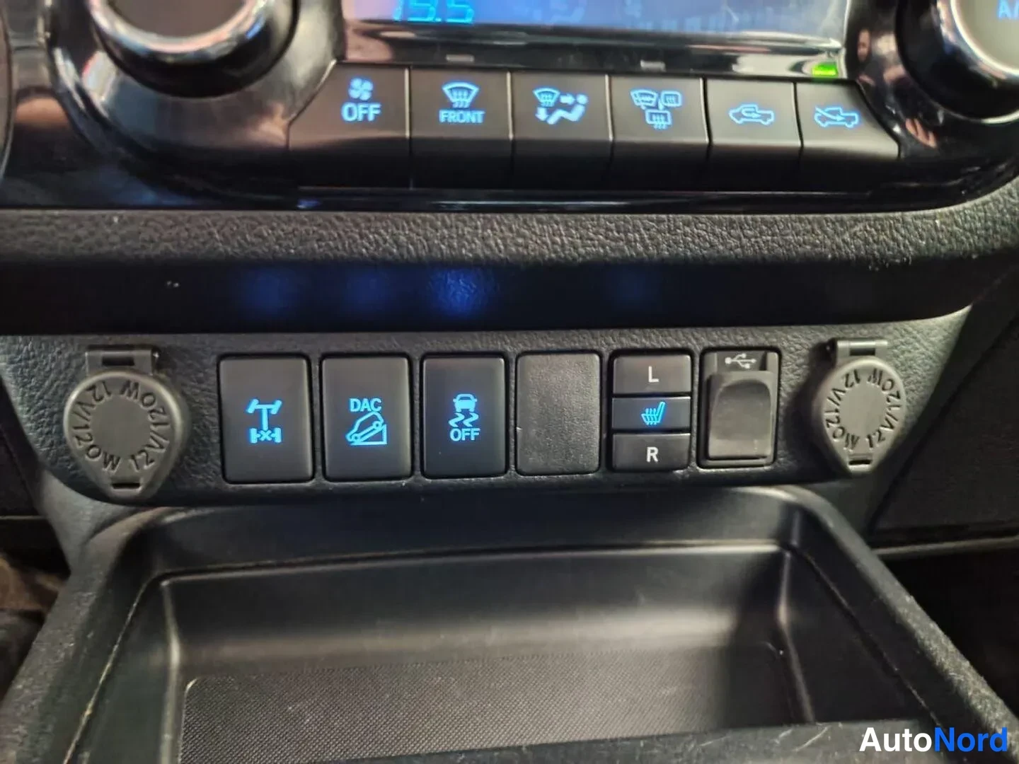 Muu: Keskikonsolin kytkinpaneelin lähikuva: DAC- ja Off-Road-kytkimet, lämmitettävien istuinten L/R-napit, USB-portti ja 12 V-pistorasiat.