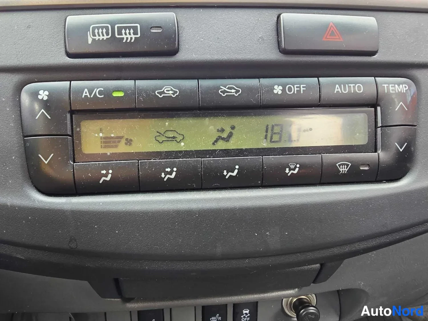 Muu: Automaattisen ilmastoinnin ohjauspaneelin lähikuva, näyttö 18 °C, painikkeet A/C ja AUTO.